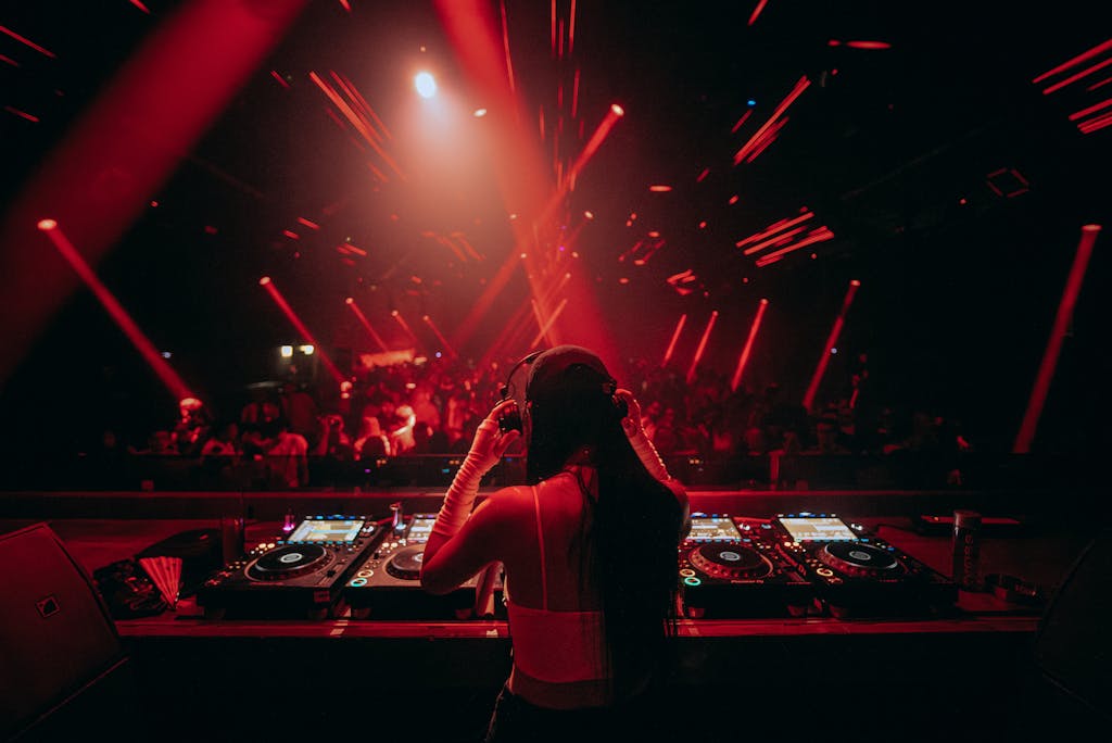 Energetic nightclub with female DJ mixing music under vibrant red lights.
